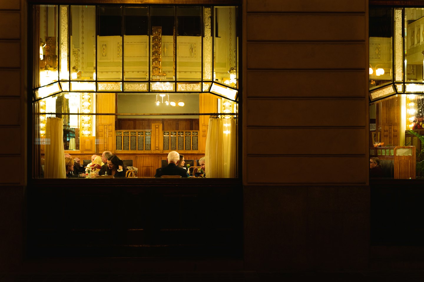Patrons dine and socialize inside a restaurant with wooden paneling.